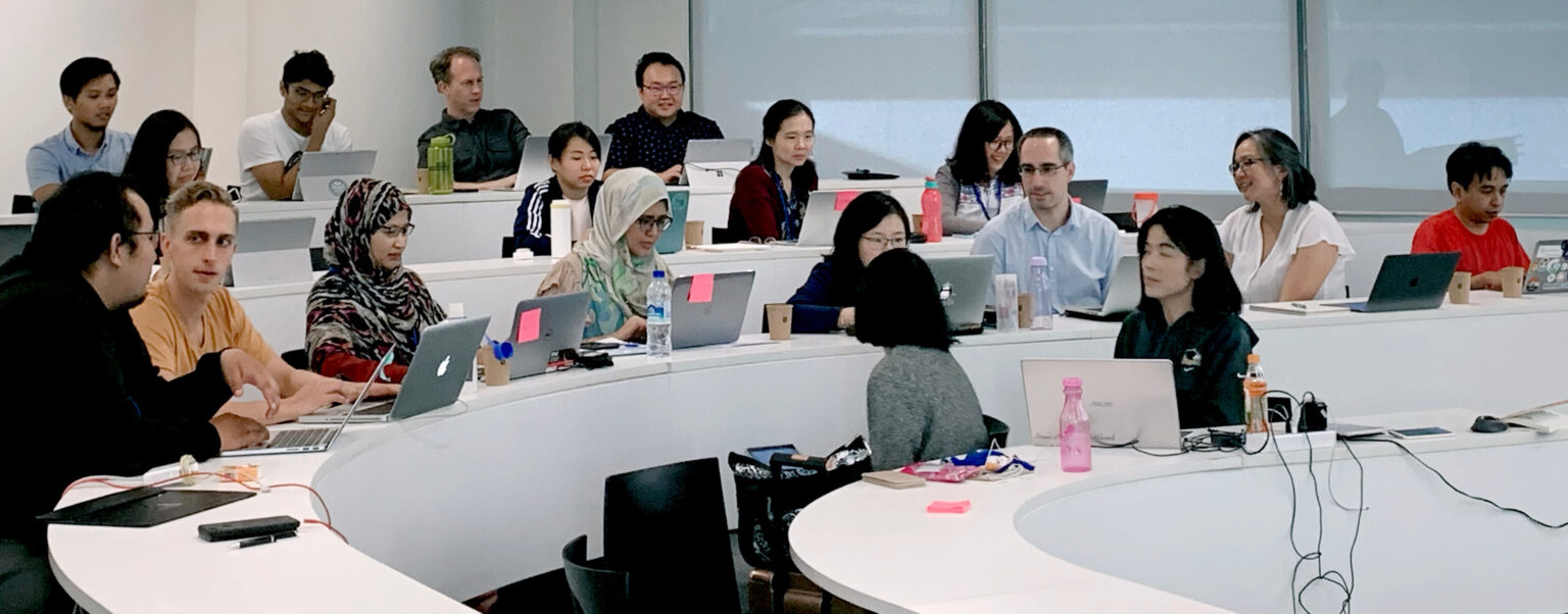 A group of adult learners discussing a topic in a modern classroom.